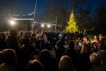 Beleuchteter Weihnachtsbaum inmitten einer Menschenmenge bei einer abendlichen Veranstaltung im Freien.