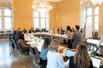 Bildbeschreibung: Mehrere Personen sitzen an einem Konferenztisch.