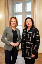 Bildbeschreibung: Zwei Frauen stehen vor einem Fenster.