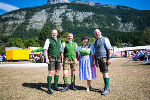 Bildbeschreibung: Gruppe in Tracht vor Bergkulisse. Festzelt im Hintergrund.