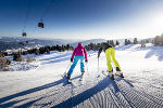 Zwei Skifahrer fahren durch eine tiefverschneite Winterlandschaft.