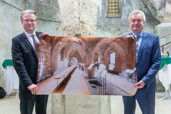 LH Christopher Drexler und LH-Stv. Anton Lang in der gotischen Einsäulenhalle der Grazer Burg mit der Visualiserung, wie der Raum am Ende der Revitalisierung aussehen könnte. © Land Steiermark/Robert Binder; Verwendung bei Quellenangabe honorarfrei